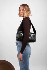 Cartera estilo baguette de cuero negro, de silueta alargada, con cierre en diagonal y correa para el hombro.