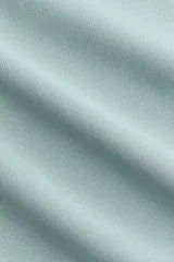 Top entallado sin mangas en punto pesado color verde menta, con escote redondo, pliegues en un lateral y bajo asimétrico.