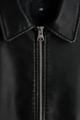 Campera negra de tejido revestido con cuello, cierre frontal y bolsillos laterales. Cuenta con puños y bajo con elástico revestido.