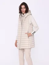 Chaleco largo color beige, matelaseado, con capucha y cierre frontal.