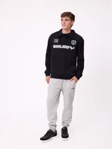 Babucha jogger color gris oscuro, con cintura elástica ajustable con cordón, bolsillos laterales y puños elásticos en los tobillos. Presenta un logo estampado en el muslo izquierdo.