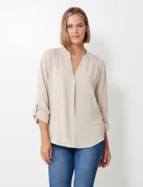Blusa de gasa color beige, marca Floral & Ivy, con cuello a la base y escote en V. Las mangas son largas y regulables con presilla y botón.