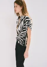 Camisa de manga corta con estampado de hojas en blanco y negro, cuello camisero y cierre delantero con botones.