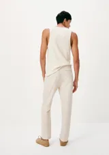 Pantalón chino de corte recto, color beige, con cierre frontal de botón y cremallera, y bolsillos laterales.