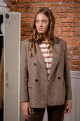 Chaqueta de corte sastre en color marrón con textura jaspeada, diseño de doble botonadura con cuatro botones frontales, solapas clásicas y bolsillos con solapa.