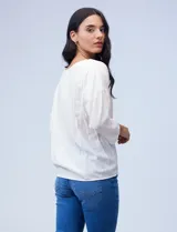 Blusa texturada color blanco, con escote en V con bordado, manga larga de largo regulable y ruedo con nudo.