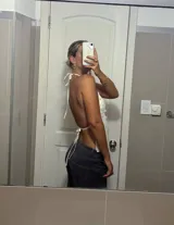 Top halter color beige claro, ajustado al cuerpo, con escote pronunciado en V y cubierto de lentejuelas redondas. Se ajusta mediante tiras en el cuello y la espalda.