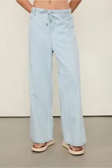 Pantalón de jean celeste de tiro bajo, calce amplio y largo extendido. Presenta cintura elástica con lazo para ajustar.