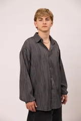 Camisa de manga larga con corte relajado, confeccionada en microfibra con estampado abstracto de líneas verticales en tonos grises. Presenta cuello clásico, cierre frontal con botones, bolsillo en el pecho con el nombre de la marca bordado.