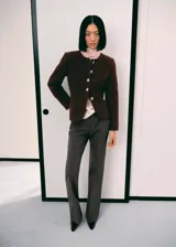 Chaqueta entallada de tejido bouclé color marrón, con cuello redondo, manga larga y cierre frontal de botones con efecto joya. Incluye forro interior.