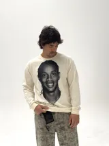 Remera de manga larga color beige con estampado fotográfico frontal de Ronaldinho en blanco y negro. Presenta un corte oversize y cuello redondo.