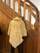 Poncho beige de piel sintética con cuello alto y corte asimétrico.