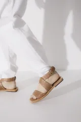 Sandalias bajas de cuero negro con tachas plateadas, tiras cruzadas y hebilla al tobillo.