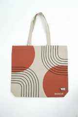 Bolso tipo tote bag beige con diseño estampado de círculos terracota y líneas negras curvas. Cuenta con doble asa de hombro del mismo material.