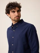 Camisa de manga larga confeccionada en algodón oxford, con cuello abotonado y cierre frontal de botones. Presenta un diseño clásico y minimalista con un pequeño logo bordado en el pecho.