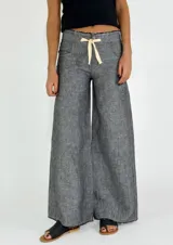 Pantalón de lino color ladrillo, de corte palazzo y tiro alto, con bolsillos laterales y cordón ajustable en la cintura.