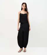 Pantalón balloon de crepé negro, de corte amplio y cintura elástica, con detalles de encaje en los laterales y puños inferiores elastizados.
