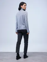 Polera de tejido fino, color rosado, con cuello alto, manga larga y detalle de tajo en los puños.