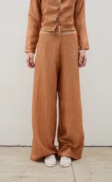 Pantalón tipo palazzo de corte recto y holgado, confeccionado en tela con textura arrugada y acabado satinado, con cierre invisible en la parte trasera.