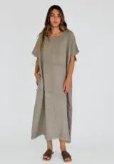 Vestido midi de lino en color beige, con diseño holgado, cuello redondo y detalles de costuras con terminaciones desflecadas en el frente y las mangas.