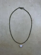 Collar de tres niveles compuesto por cuentas pequeñas de piedra natural y metal, con tres dijes en forma de corazón de piedra natural facetada en tonos rosado, negro y gris, enmarcados en metal dorado.