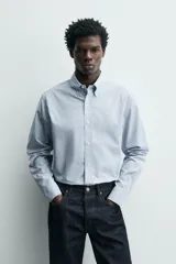Camisa de corte regular fit confeccionada en tejido de algodón con estampado de microcuadros. Presenta cuello abotonado, manga larga con puños abotonados y cierre frontal con botones.
