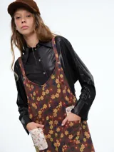 Mono de corte holgado con estampado floral sobre fondo marrón. Presenta tirantes ajustables, bolsillos frontales con parches en contraste y diseño de pierna ancha.
