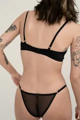 Sostén negro sin aro ni relleno, confeccionado en tela transparente con tirantes regulables y cierre posterior de gancho.
