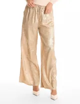 Pantalón de corte wide leg en tejido laminado metalizado color gris. Presenta pretina ancha elastizada con lazo de ajuste y bolsillos delanteros.