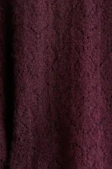 Buzo corto de punto pointelle color bordó, con cuello redondo y ribete acanalado de volados en el bajo. Cuello y puños festoneados.