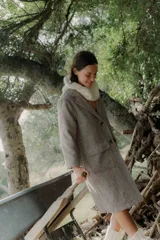 Tapado de corte recto y largo midi, confeccionado en tejido con textura de espiga en tonos grises. Presenta solapas clásicas, cierre frontal con botones y bolsillos laterales amplios con solapa.