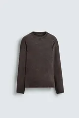 Camiseta de manga larga color marrón oscuro con efecto lavado (acid wash) y corte relajado. Presenta cuello redondo y aberturas laterales en el bajo.