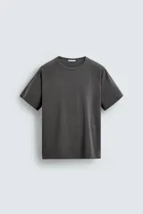 Camiseta relaxed fit color gris oscuro, confeccionada en tejido ligero de algodón con elasticidad. Presenta cuello redondo y manga ranglán corta.