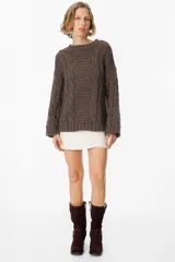 Sweater de tejido de punto con diseño de trenzas verticales, cuello redondo y silueta holgada.