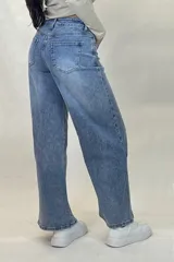 Pantalón de jean estilo wide leg con tiro alto, costuras verticales decorativas en el frente y corte diagonal en la parte inferior de las piernas.