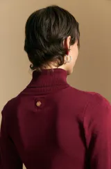 Polera de tejido fino color negro, con cuello alto y mangas largas con terminación sutilmente fruncida. Diseño ajustado al cuerpo.