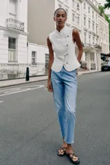 Jeans de tiro alto con diseño mom fit, tobilleros, de cinco bolsillos y cierre frontal con cremallera y botón, en color azul claro con efecto deslavado.