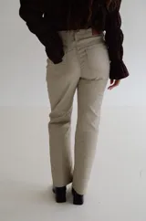 Pantalón de tiro alto con acabado engomado, de corte recto y pierna con leve apertura. Presenta cierre frontal con botón y bolsillos laterales.