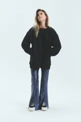 Buzo negro oversize de frisa esmerilada con cuello alto, hombros caídos, bolsillos laterales y estampa en la espalda con el logo de la marca en animal print.