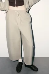 Pantalón de tiro alto con cintura elástica ajustable mediante cordón. Presenta un corte recto y holgado con bolsillos laterales y traseros.