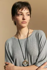 Remera de calce relajado con silueta fluida, confeccionada en tejido de viscosa con elastano. Presenta cuello redondo, mangas cortas y un diseño minimalista de caída suave.