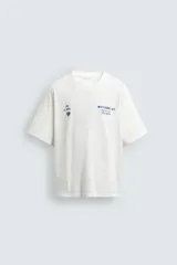 Camiseta de corte relajado con cuello redondo y manga corta. Presenta un diseño con estampados en tono azul con efecto lavado en la parte frontal.
