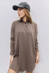 Vestido corto de tejido acanalado color marrón chocolate, con cuello polo y cierre frontal de botones. Presenta mangas largas con puños ajustados y un corte holgado.