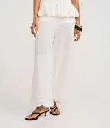 Pantalón estilo aladín blanco, de tejido piqué texturizado, con cintura elástica y puños ajustados en los tobillos.