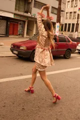 Camisa larga tipo sobrecamisa o abrigo ligero, color verde menta pálido con estampado floral en tono amarillo claro. Presenta escote en V con atado frontal mediante lazos, mangas largas con detalle fruncido y puños con flecos en tono turquesa.