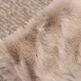 Bufanda de tejido texturizado en tono beige, con detalle de aplique de piel sintética en uno de los extremos y terminaciones con flecos.