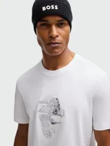 Camiseta blanca de algodón elástico con cuello redondo y manga corta. Presenta un estampado artístico con el logo de la marca en el pecho.