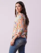 Blusa estampada de Zac & Rachel con cuello a la base, escote en V y botones. Tiene un bolsillo aplicado en la parte delantera, mangas largas regulables con presilla y botón, y terminación anudada opcional.