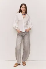 Camisa blanca de corte amplio y largo cropped, con mangas abullonadas, puño ajustado, cuello clásico y abertura en V con botones al tono.