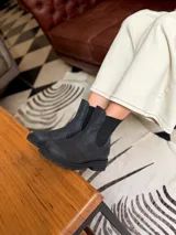 Bota tipo chelsea de cuero negro, con paneles elásticos laterales y suela track dentada.